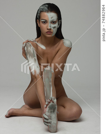 Portrait of a beautiful tanned girl with clay on her face and body. Art photography. Gentle skin and hair care, spa and makeup Portrait of a beautiful tanned girl with clay on her face and body. Art photography. Gentle skin and hair care, spa and makeup 74882964