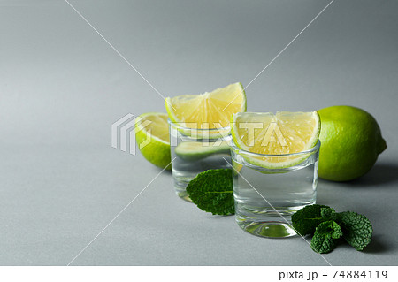 Shots, lime slices and mint on gray background Shots, lime slices and mint on gray background 74884119