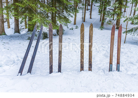 Old wooden skis stuck in the snow in the forrest. Vintage winter sports background. Old wooden skis stuck in the snow in the forrest. Vintage winter sports background. 74884934
