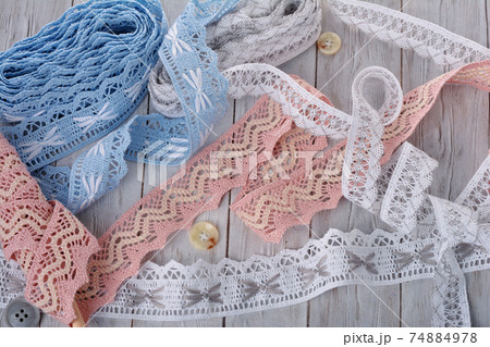 Pile of vintage cotton tapes and round buttons on wood background 74884978
