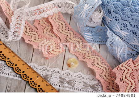 Pile of vintage cotton tapes and round buttons on wood background 74884981