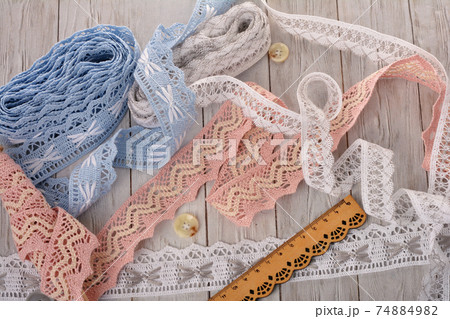 Pile of vintage cotton tapes and round buttons on wood background 74884982