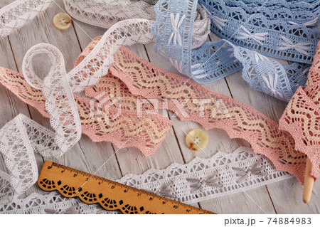Pile of vintage cotton tapes and round buttons on wood background 74884983