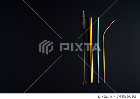 The modern trend caring for the environment. Self kit of reusable metal beverage straws of various diameters, colors and shapes with cleaning tool. On black background 74886692