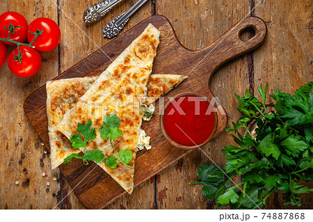 Close-up baked national oriental pastry with cheese filling, tomato sauce, greens, traditional Close-up baked national oriental pastry with cheese filling, tomato sauce, greens, traditional 74887868