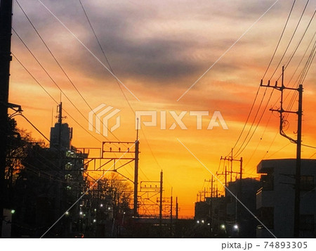 夕暮れのオレンジ色の空と電線が連なる街並みのシルエット風景 夕暮れのオレンジ色の空と電線が連なる街並みのシルエット風景 74893305