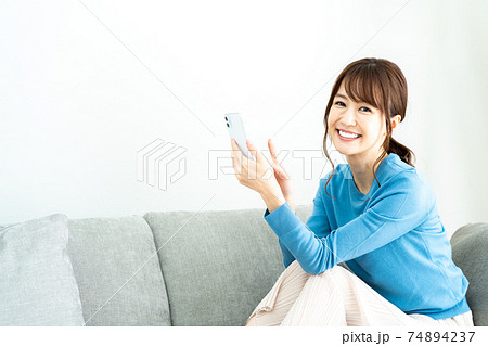 リビングのソファでスマホを使う女性 74894237