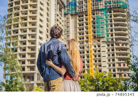 Couple looking at their new house under construction, planning future and dreaming. Young family dreaming about a new home. Real estate concept Couple looking at their new house under construction, planning future and dreaming. Young family dreaming about a new home. Real estate concept 74895345