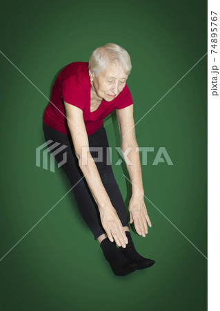 Senior woman wearing sportswear while gymnastic exercising in the living room 74895767