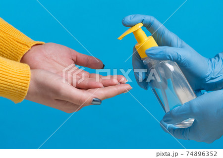 concept of protection against viruses and bacteria, hands are treated with a disinfectant, on a blue background concept of protection against viruses and bacteria, hands are treated with a disinfectant, on a blue background 74896352