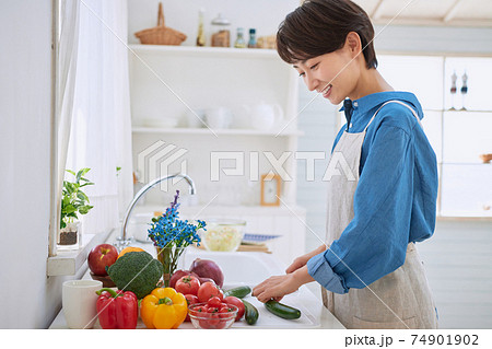 キッチンで料理をするミドル女性の写真素材