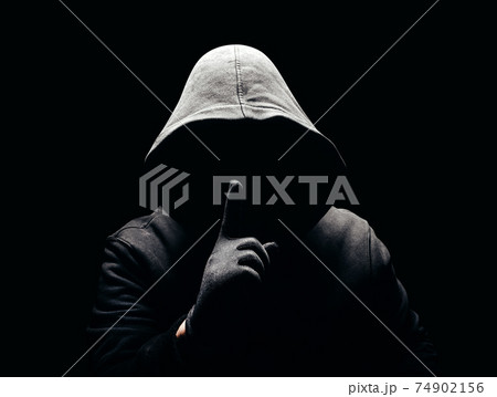 Photo of a scary horror man in hoodie showing silence hand sign in dark. Photo of a scary horror man in hoodie showing silence hand sign in dark. 74902156