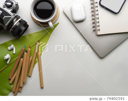 Workspace with camera, smartphone, coffee cup, supplies, copy space and leaf decorated on the table 74902591