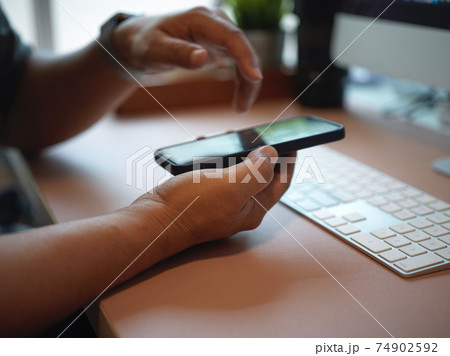 Male hands using smartphone on computer desk in office room 74902592