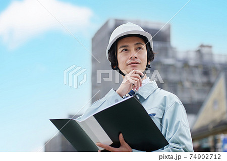 建設現場に立つ作業服の男性 建設現場に立つ作業服の男性 74902712