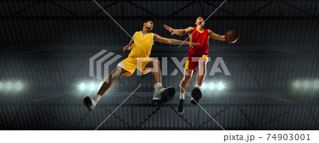 Young basketball players in competitive fight, motion in flight on black background, look from the bottom. Concept of sport, movement, energy and dynamic. Young basketball players in competitive fight, motion in flight on black background, look from the bottom. Concept of sport, movement, energy and dynamic. 74903001