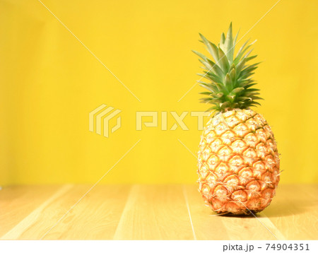 Ripe pineapple on a yellow wooden background 74904351