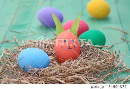 straw basket with easter eggs on wooden background straw basket with easter eggs on wooden background 74904375