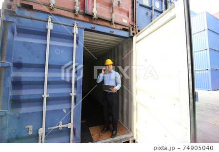 Engineer or supervisor checking and control loading Containers box from Cargo at harbor.Foreman control Industrial Container Cargo freight ship at industry.Transportation and logistic concept. 74905040