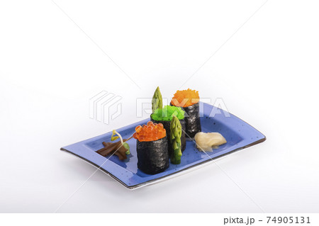Close up of beautiful maki pieces with pickled ginger and asparagus on a small tray on a light background. Sushi and healthy food concept. 74905131