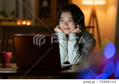 夜リビングでパソコンを見る若い女性 夜リビングでパソコンを見る若い女性 74906114