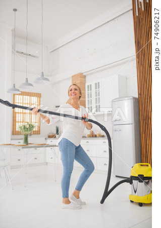 Woman with vacuum cleaner having fun finishing cleaning 74906217