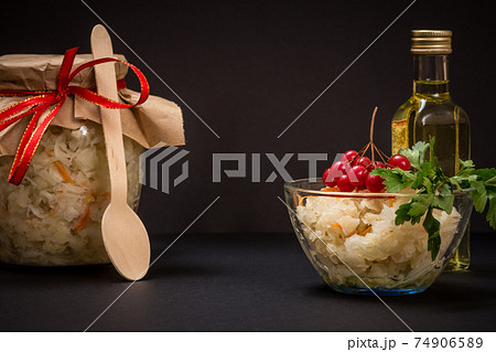Fermented cabbage with herbs and spices in glass bowl and jar on the black background 74906589