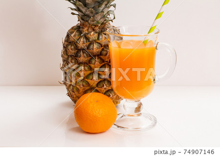 Fresh tropical fruits and glass of juice on white background. 74907146