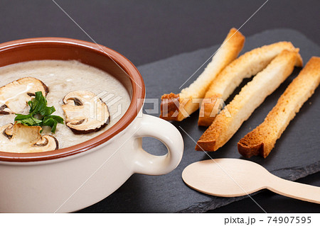 Cream soup with mushrooms in porcelain bowl on black background. 74907595
