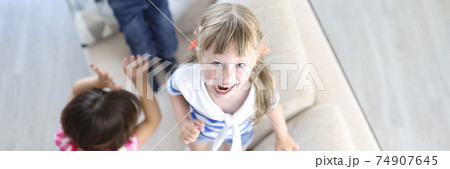 Boy and girls laugh and jump on couch at home. 74907645