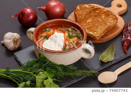 Ukrainian traditional borsch with rye bread on black background. Ukrainian traditional borsch with rye bread on black background. 74907743