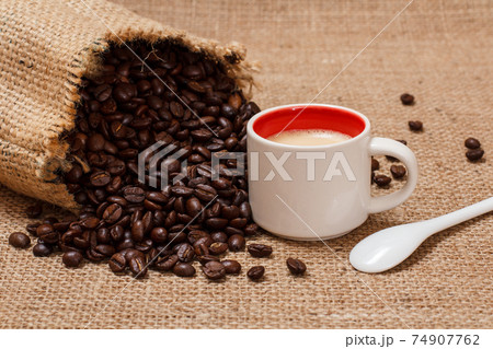 Cup of coffee and roasted coffee beans in a canvas sack. Cup of coffee and roasted coffee beans in a canvas sack. 74907762