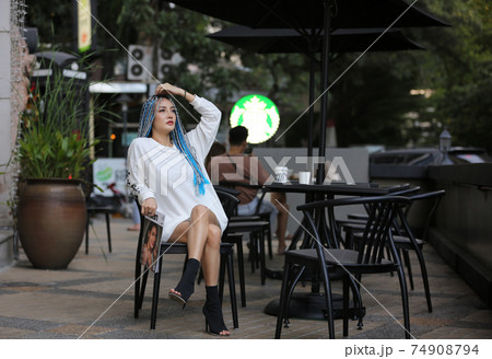 Happy stylish young hipster woman with long blue hair pink jacket, hat on the street in urban city. 74908794