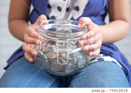 child girl holding jar of coins close up  74912619