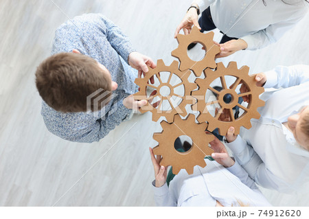 Business people holding wooden gears in office top view 74912620