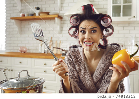 Funny inexperienced housewife feeling stressed and helpless while cooking a meal 74913215