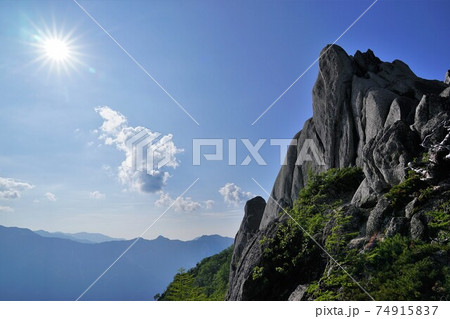 餓鬼岳山頂の岩峰と太陽 74915837