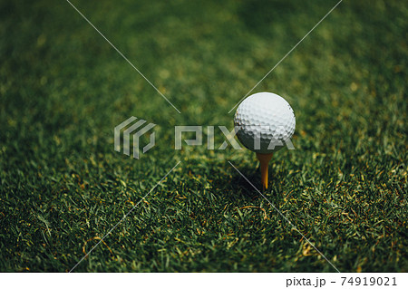 golf ball on yellow tee on green grass, closeup view 74919021