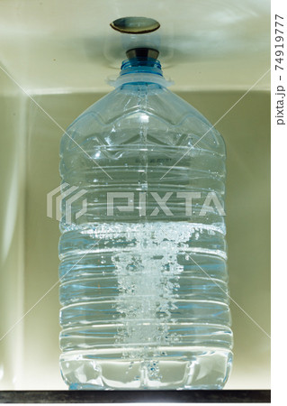 pouring water in the bottle with water dispenser 74919777