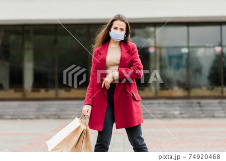 Close up portrait of a caucasian female wearing a medical mask and standing in the street and cafe 74920468