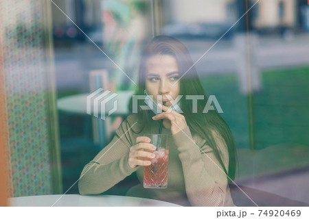 Close up portrait of a caucasian female wearing a medical mask and standing in the street and cafe 74920469