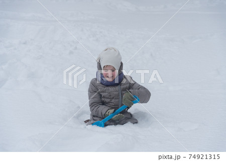 The girl is digging the snow. The child plays with a lot of snow. A rosy child in the cold. Nice walk and play 74921315