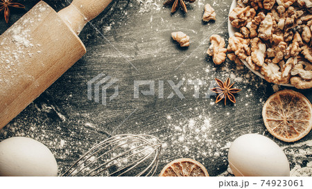 Bakery background frame. Fresh food ingredients: flour, eggs, nut and star anise, orange on black chalkboard background for bread. Still life captured from above, top view, flat lay. 74923061