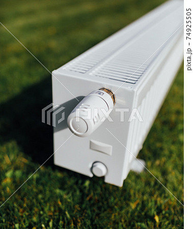 radiator on green lawn, ecological heating concept 74925505