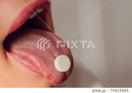 Taking pills. Woman taking pill - closeup of tongue. Taking pills. Woman taking pill - closeup of tongue. 74925983