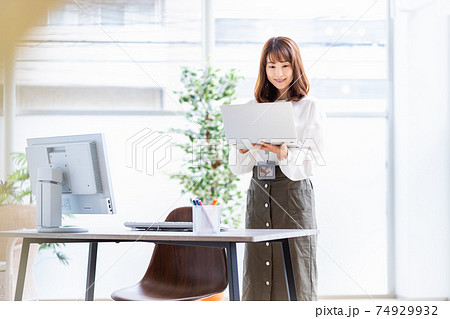 明るい室内でノートパソコンを開いて立っている女性 明るい室内でノートパソコンを開いて立っている女性 74929932