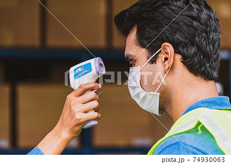 Closeup hand of Muslim woman worker using Medical Digital Infrared Thermometer measure temperature to Indian man worker before start to work after warehouse reopen again, new normal concept Closeup hand of Muslim woman worker using Medical Digital Infrared Thermometer measure temperature to Indian man worker before start to work after warehouse reopen again, new normal concept 74930063
