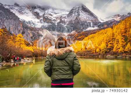 Back side of asian traveler woman looking and sightseeing over the Pearl Lake with snow mountain in autumn season in yading nature reserve, China.travel and tourism,famous place and landmark concept Back side of asian traveler woman looking and sightseeing over the Pearl Lake with snow mountain in autumn season in yading nature reserve, China.travel and tourism,famous place and landmark concept 74930142