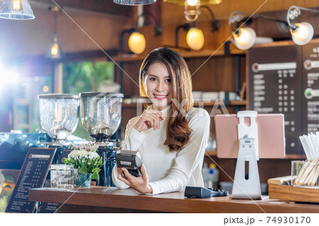 Asian Small business young owner holding contactless nfs technology machine to checking and billing for customer order in coffee shop and check money,Small business owner and startup concept 74930170