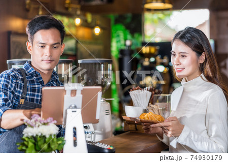 Asian Barista of Small business owner serving paper cup of coffee and Croissants bakery to young customer at the coffee counter in coffee shop and check money,Small business owner and startup concept 74930179